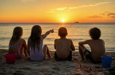 Czworo dzieci siedzi na plaży i ogląda zachód słońca nad morzem.